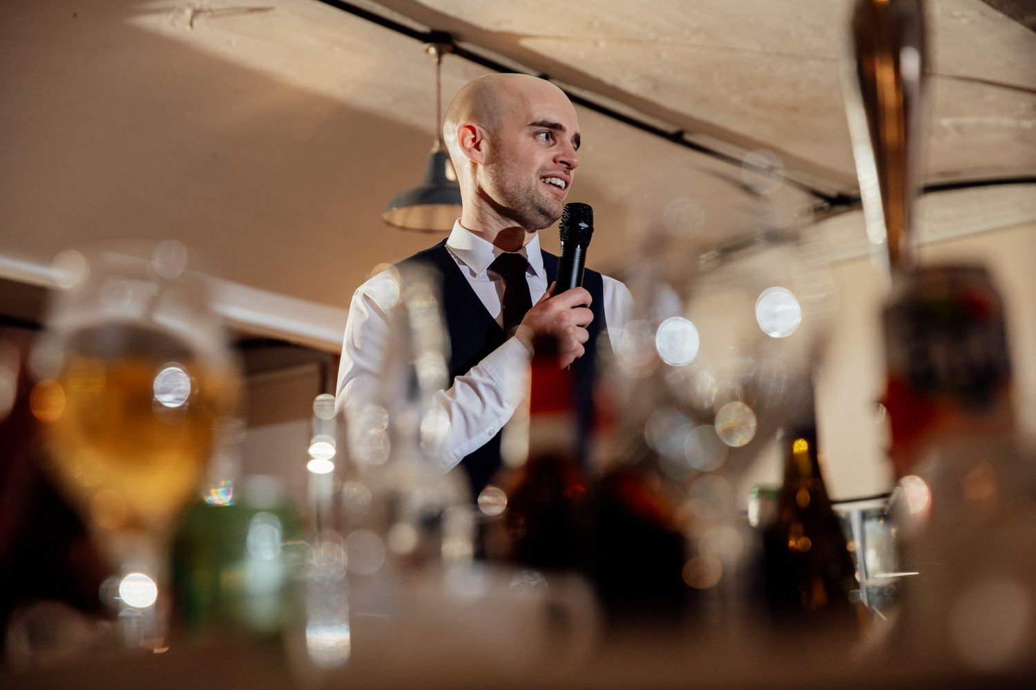 Wedding reception speeches captured with bokeh lighting and intimate atmosphere.