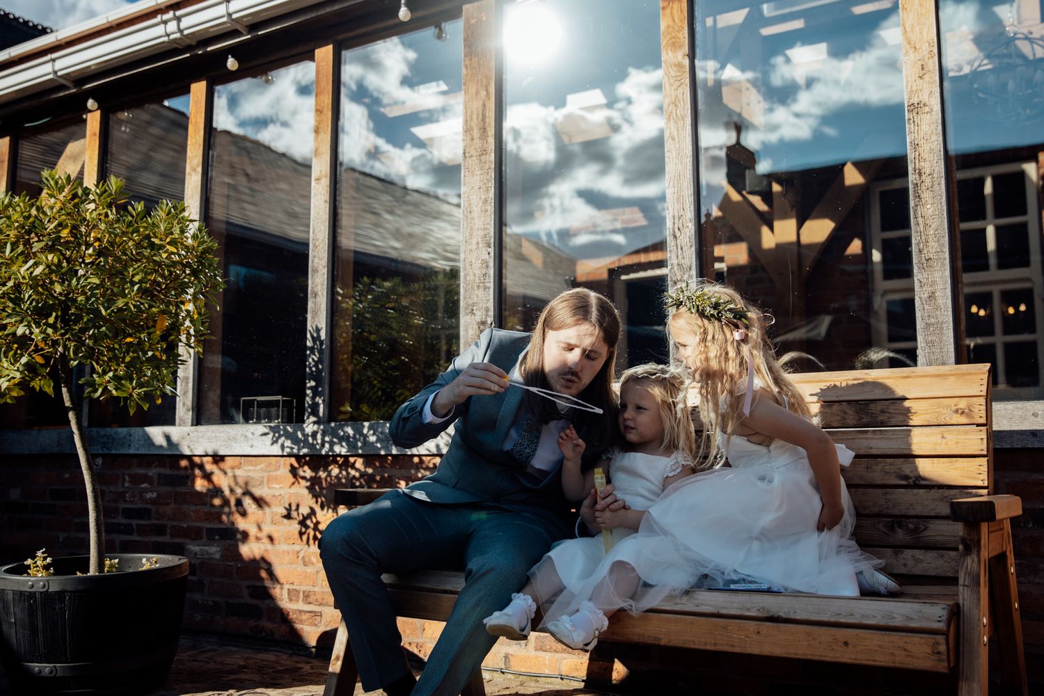 Casual wedding moment on outdoor wooden deck with sunlit backdrop.
