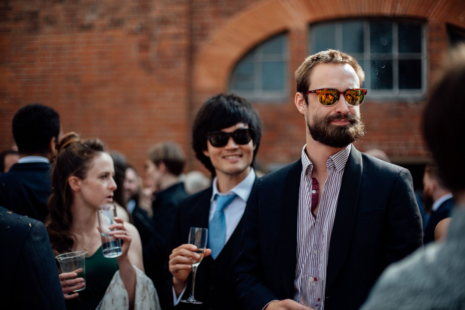 Guests gather outside a brick building during a social event.