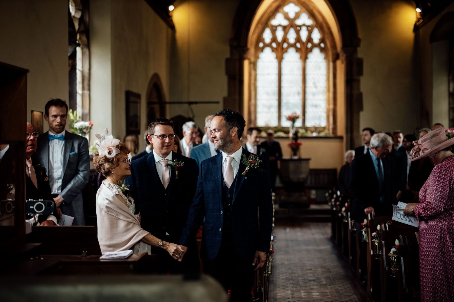 Wedding ceremony taking place inside a traditional stone church with gothic windows.