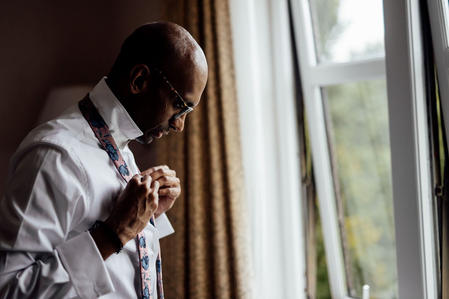 Person in formal white shirt and bow tie gazes contemplatively out window.