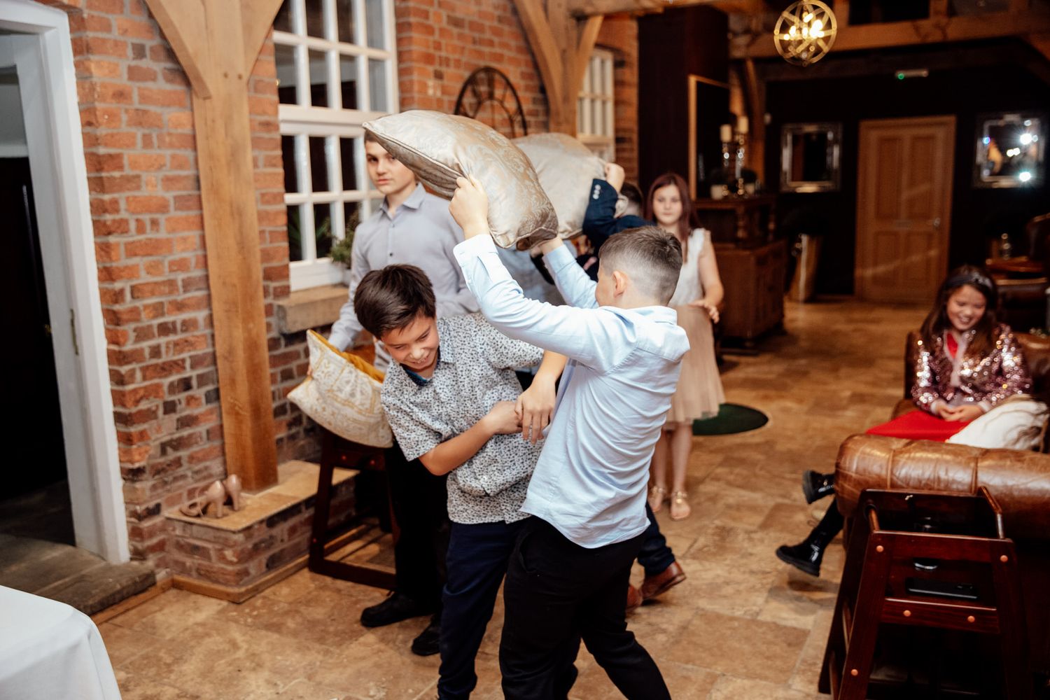 Wedding party dancing and celebrating in a rustic brick-walled venue.