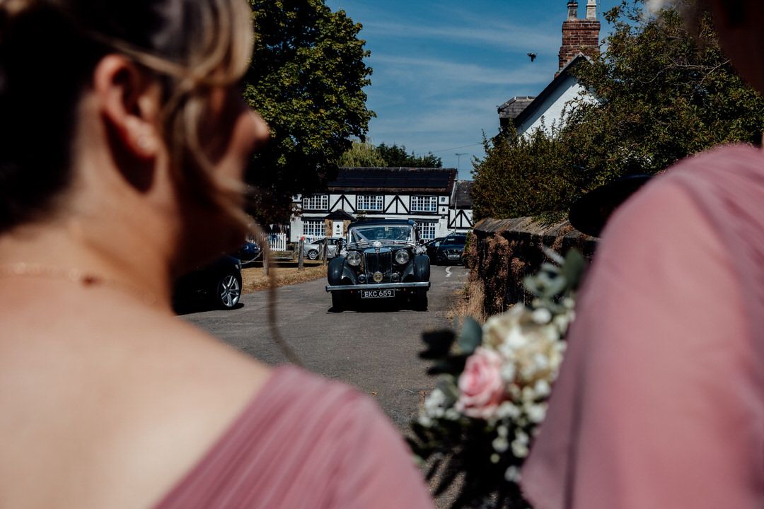 Sunny outdoor wedding venue with brick building and blue sky visible in background.