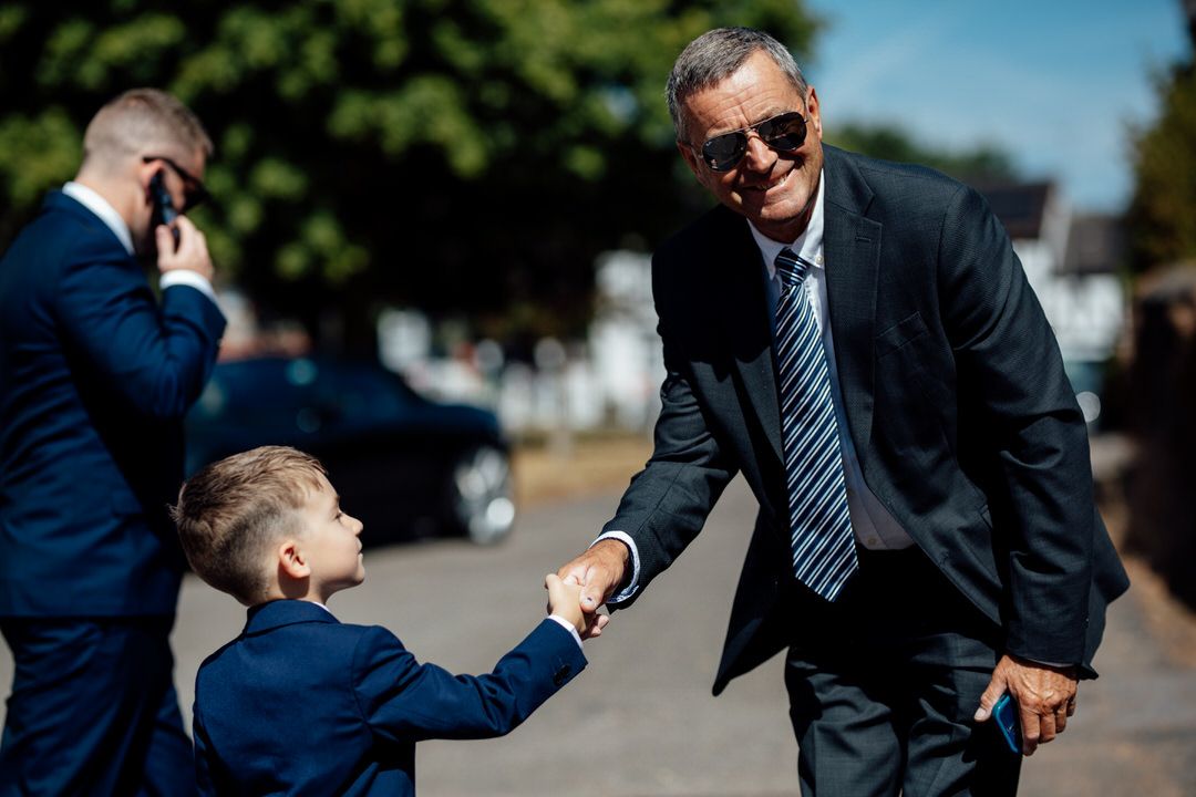 Groomsmen in dark suits and sunglasses enjoying a casual moment outside.