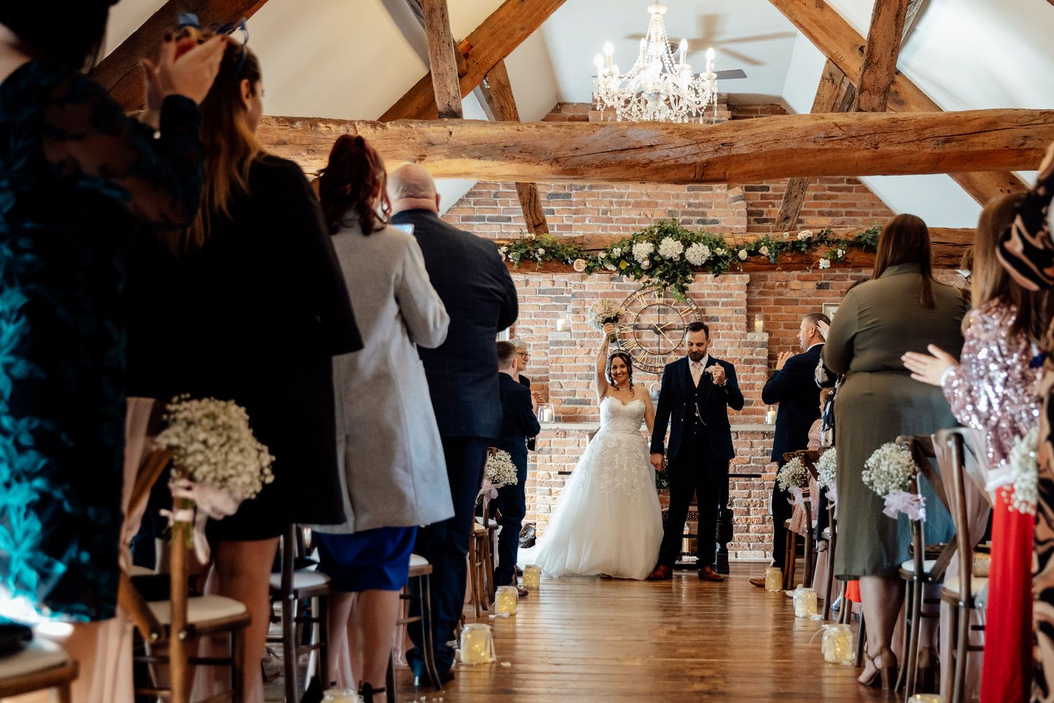 Wedding ceremony in rustic barn venue with exposed wooden beams and elegant decorations.
