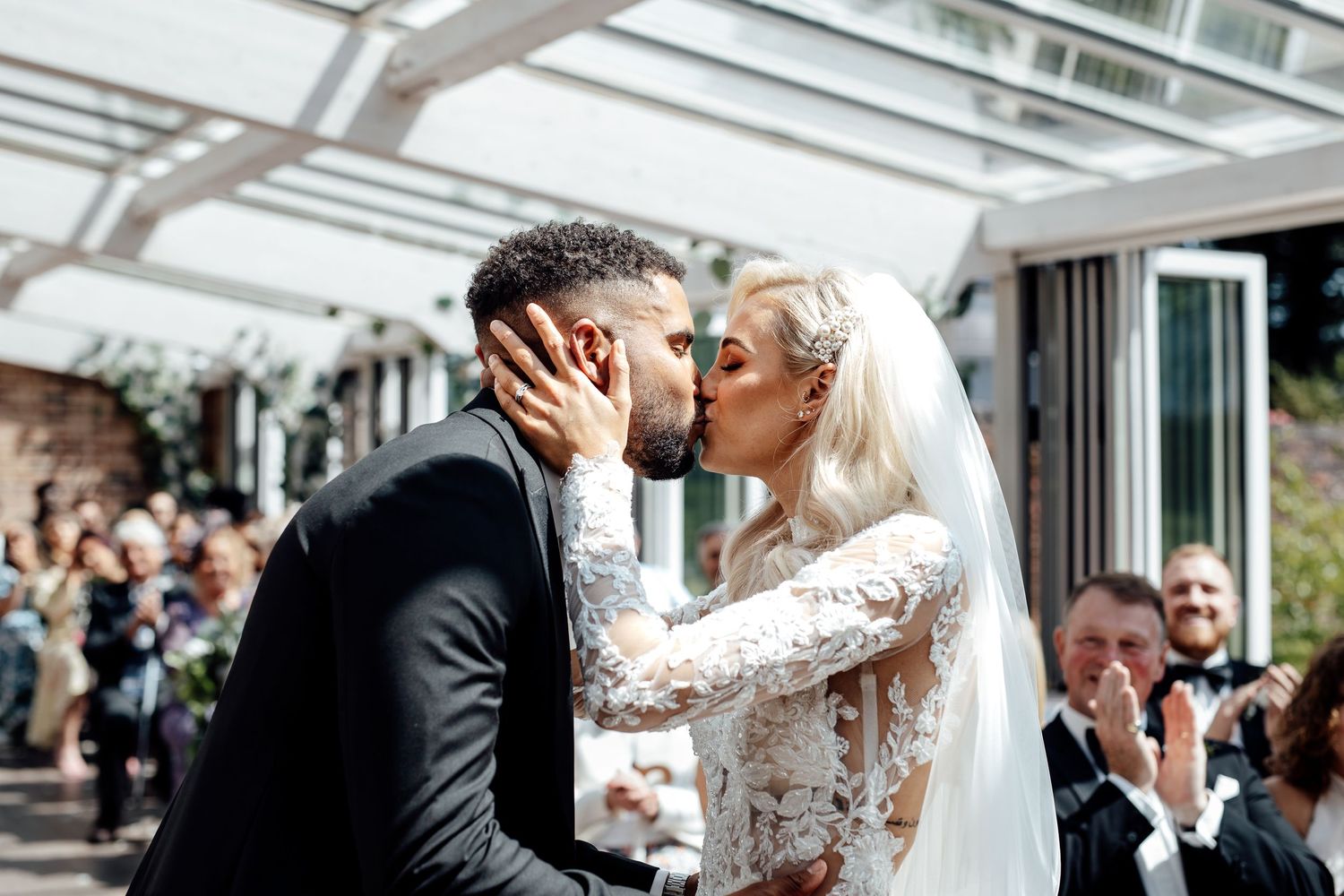 Romantic wedding ceremony moment captured under a bright glass ceiling.