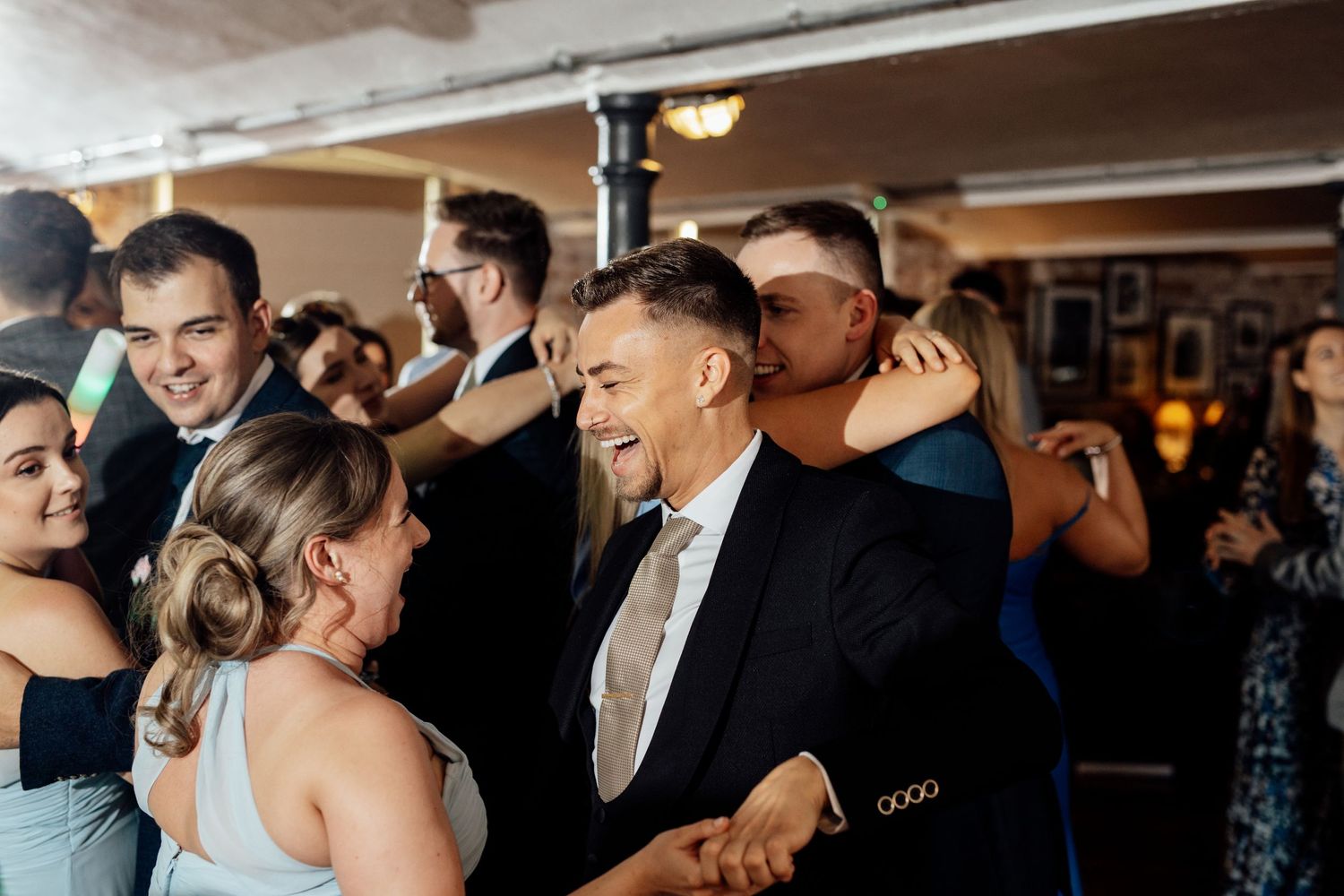 Wedding guests dancing and celebrating on a crowded dance floor.