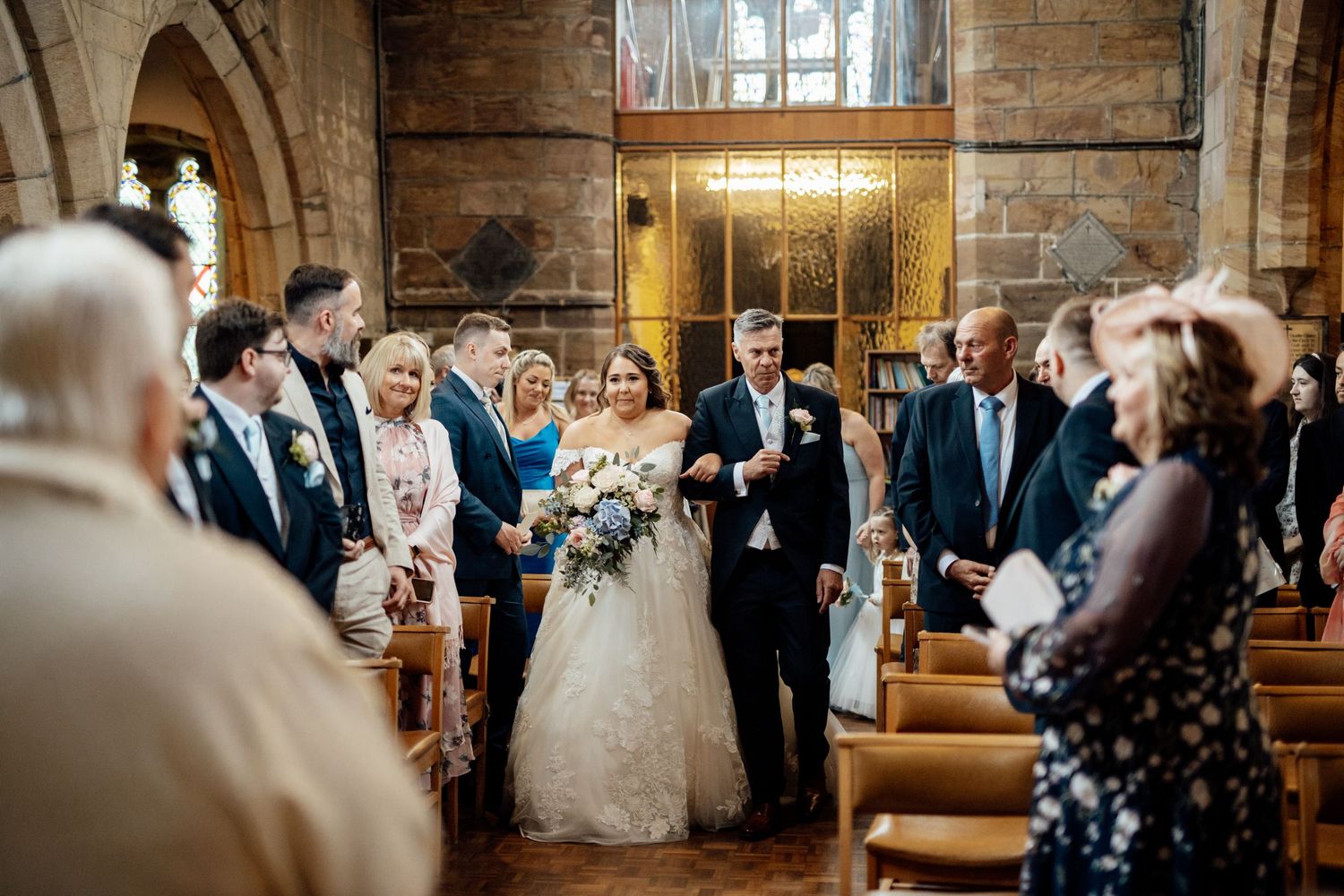 Wedding ceremony in a rustic wooden church interior with guests seated in pews.