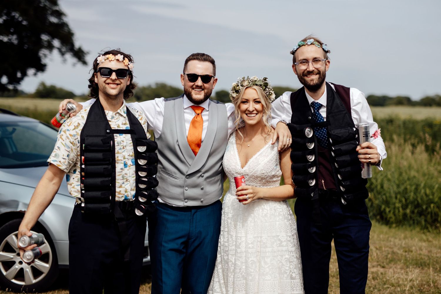 Wedding party members posing together outdoors on a sunny day.
