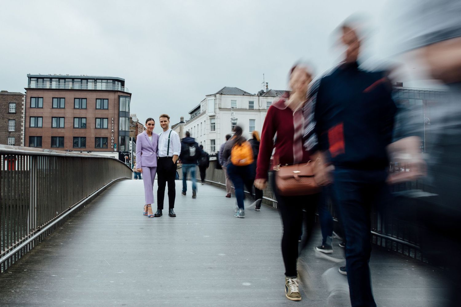 Blurred motion of people walking across an urban bridge or walkway.