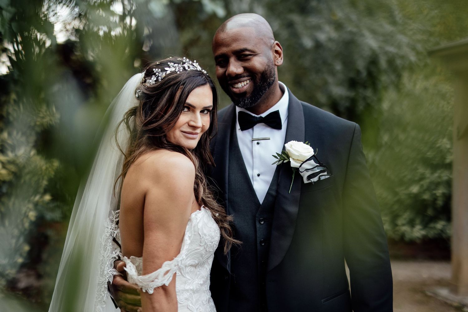 Intimate portrait of the bride and groom among garden foliage.