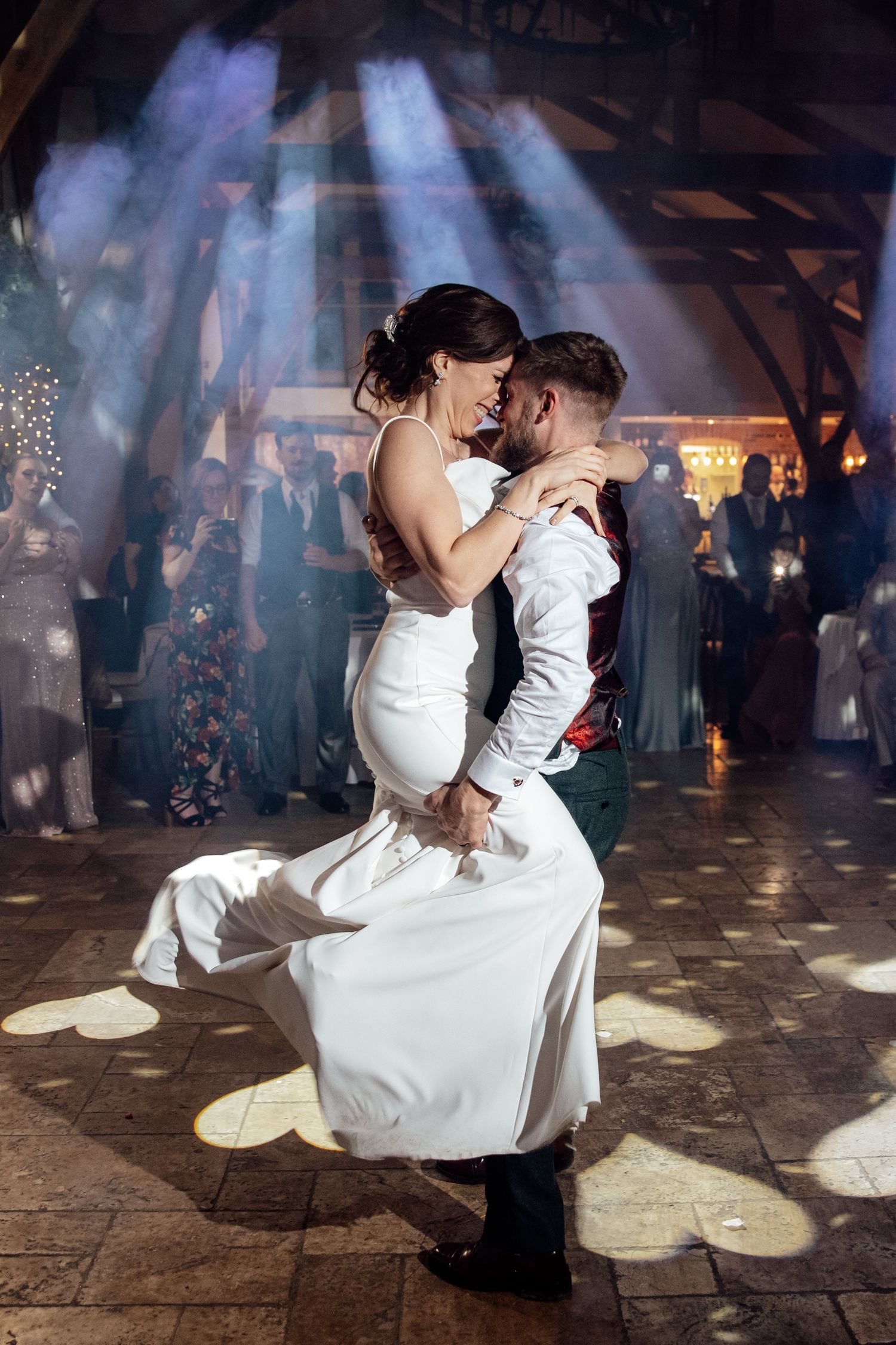 Romantic first dance at wedding reception with dramatic lighting and smoke effects on stone floor.