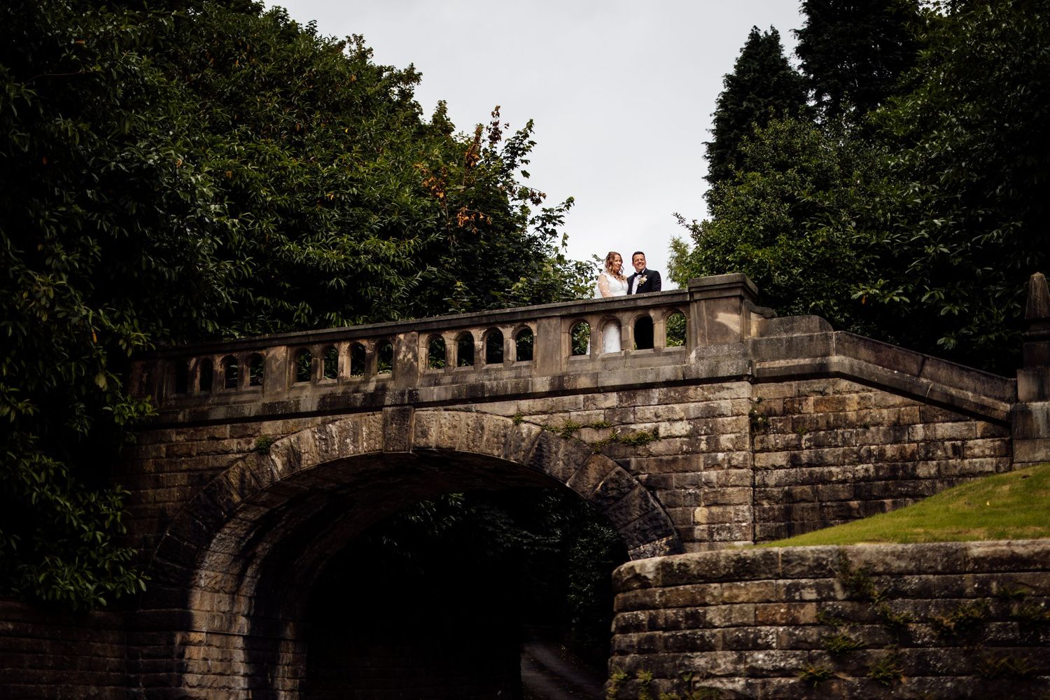 Stone wall archways and architectural details in a garden setting at dusk.