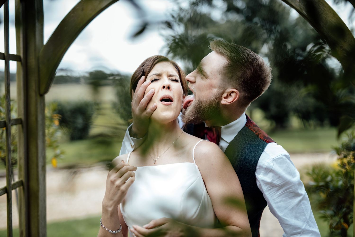 Romantic wedding portraits captured under wooden garden archway.