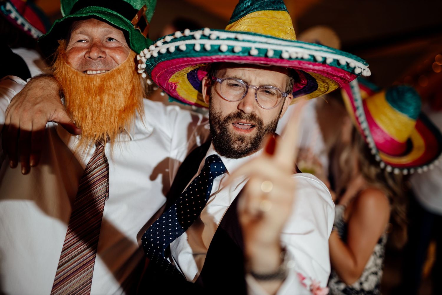 Wedding reception party guests wearing colorful sombreros and celebrating.
