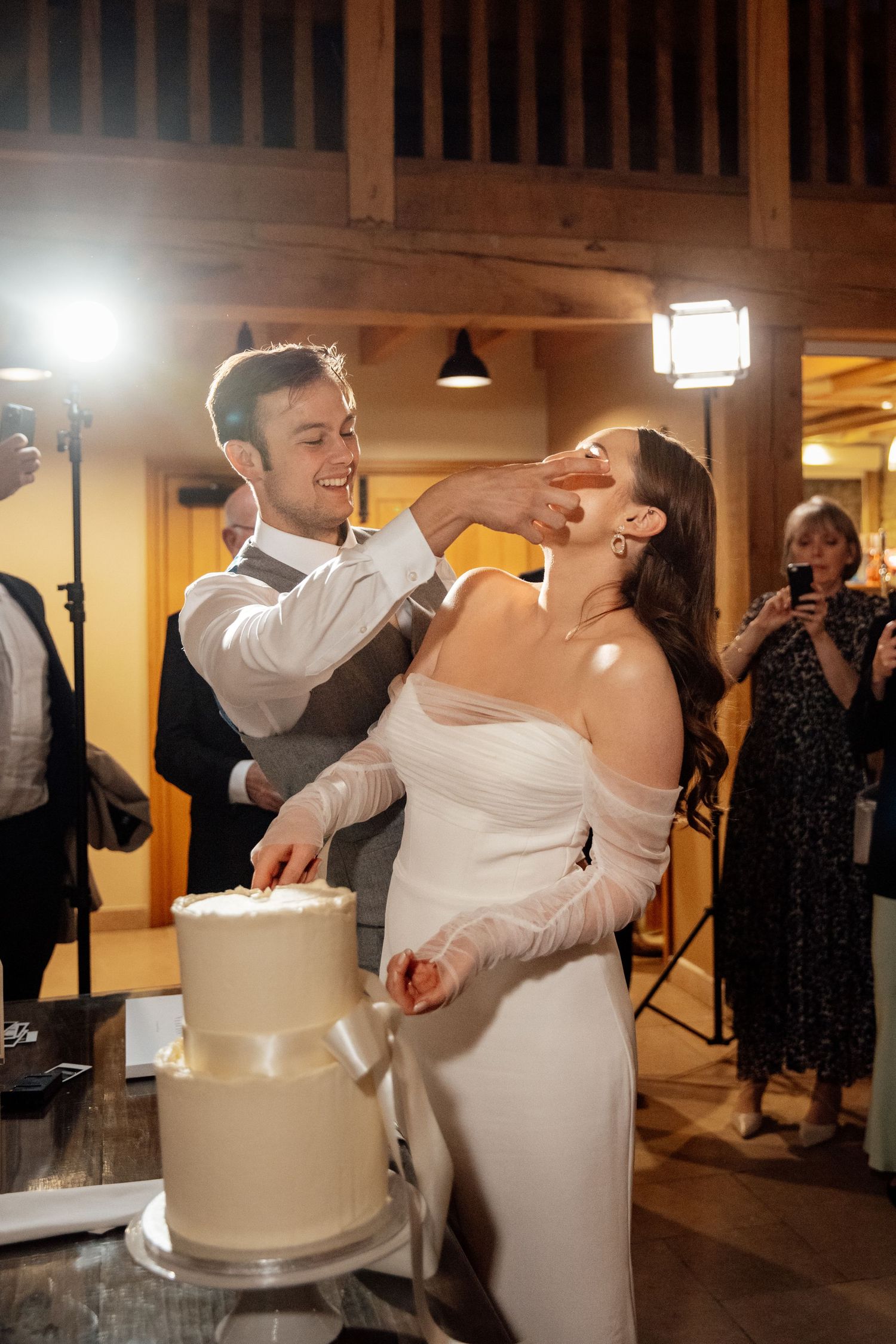 Couple sharing a playful moment while cutting their elegant white wedding cake.