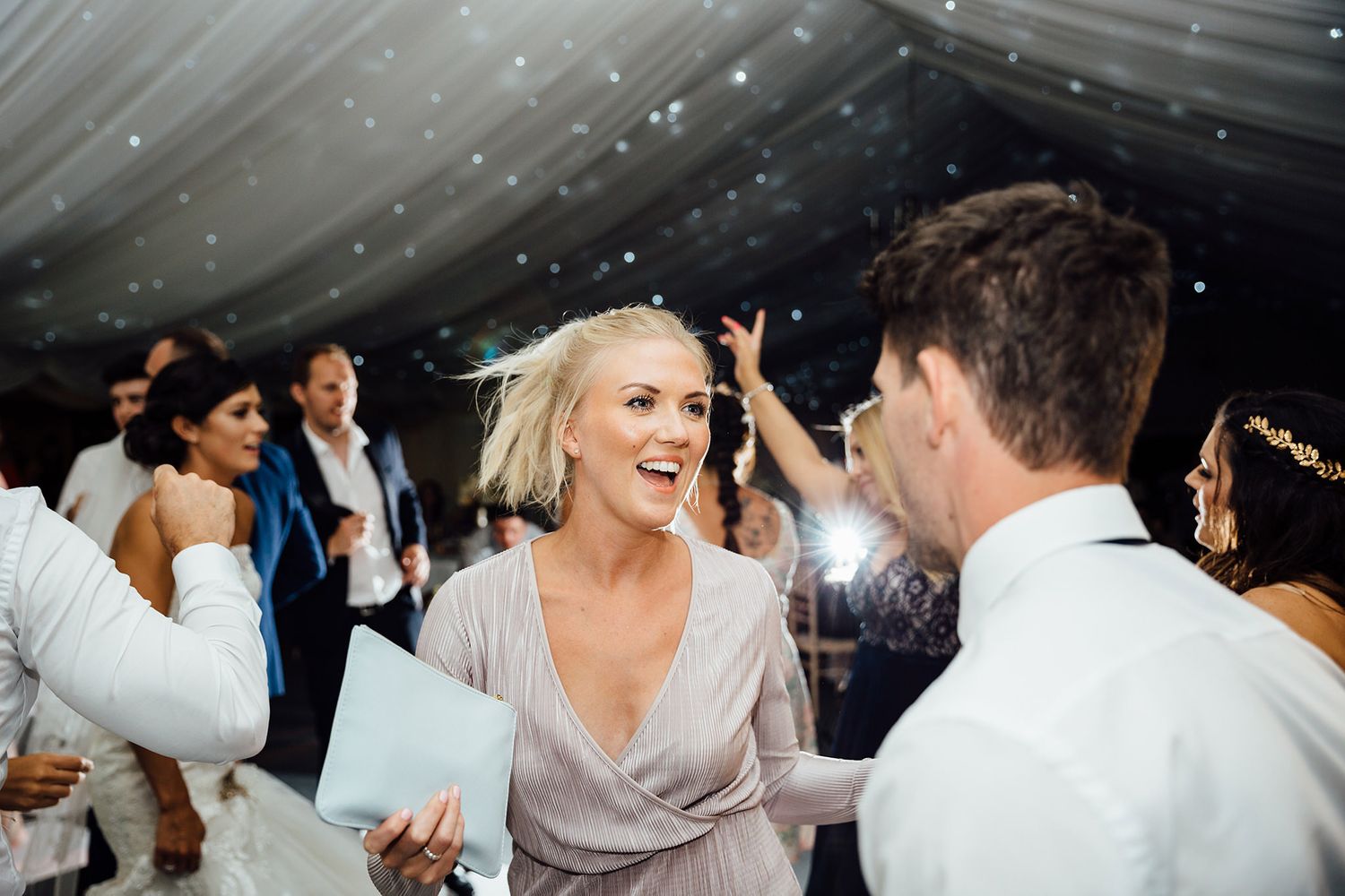Wedding reception celebration with guests dancing under twinkling lights.