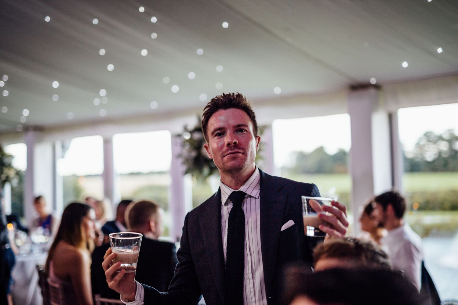 Guests in formal attire participate in a champagne toast at an elegant wedding venue.