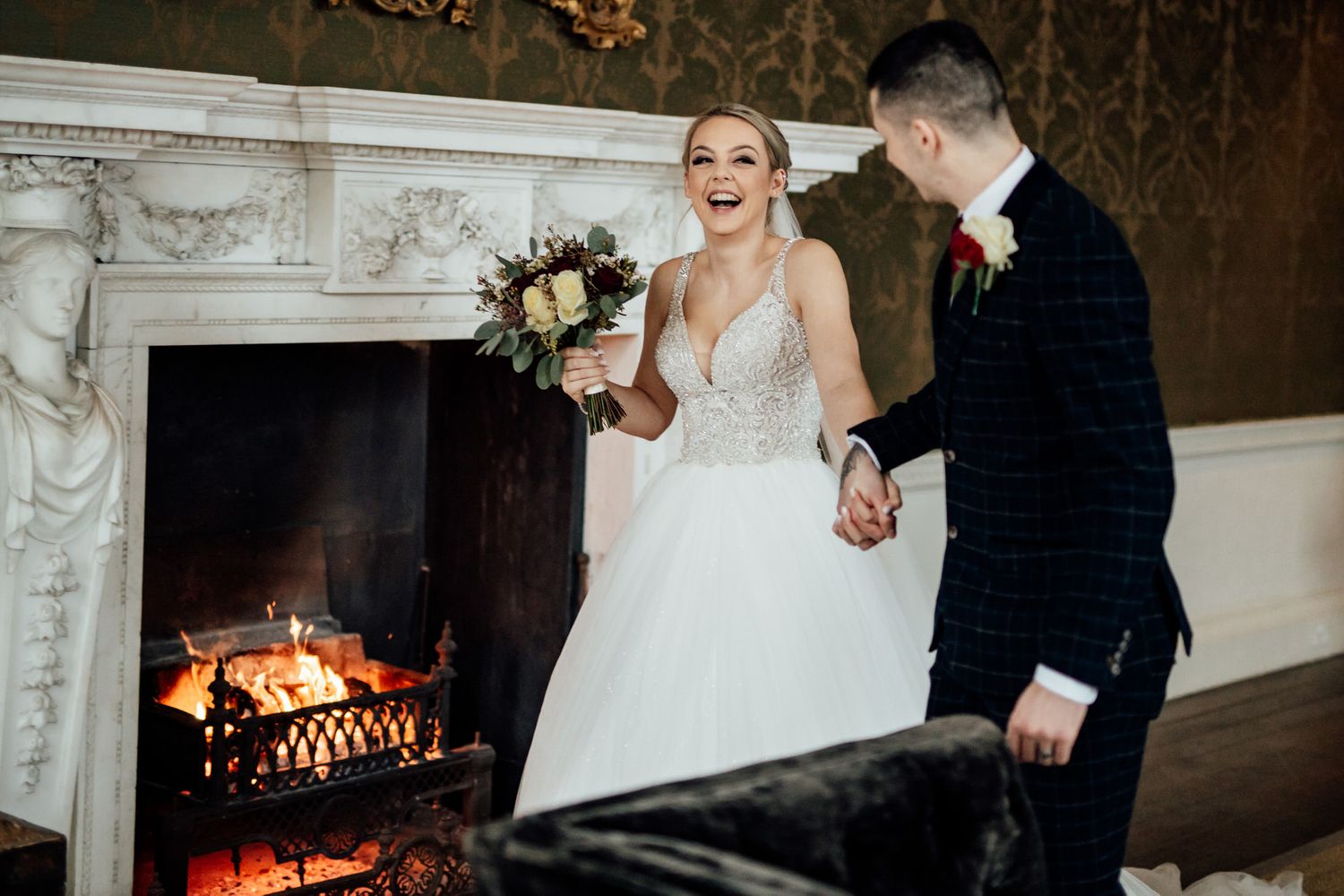 Romantic moment by fireplace in historic venue with ornate white marble mantel.