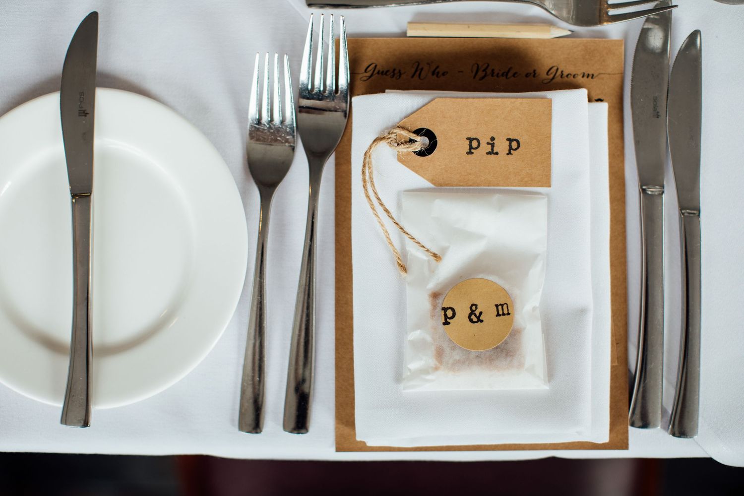 Elegant table settings with white plates and vintage name cards at wedding reception.