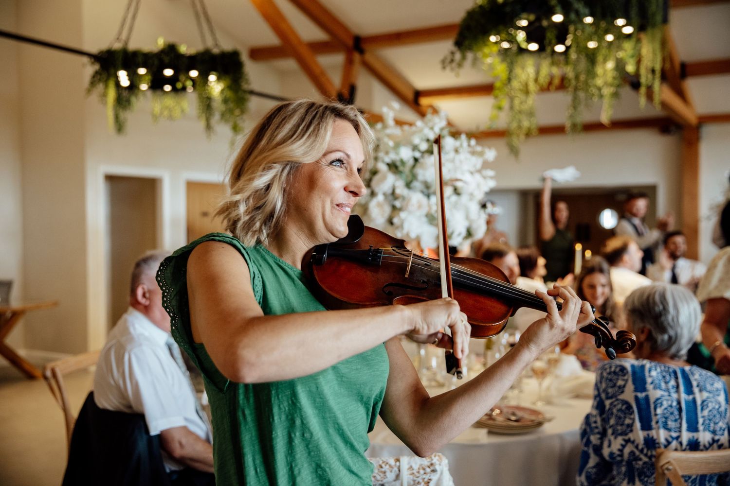 Violin musician performs at an elegant indoor wedding reception with decorative lighting.