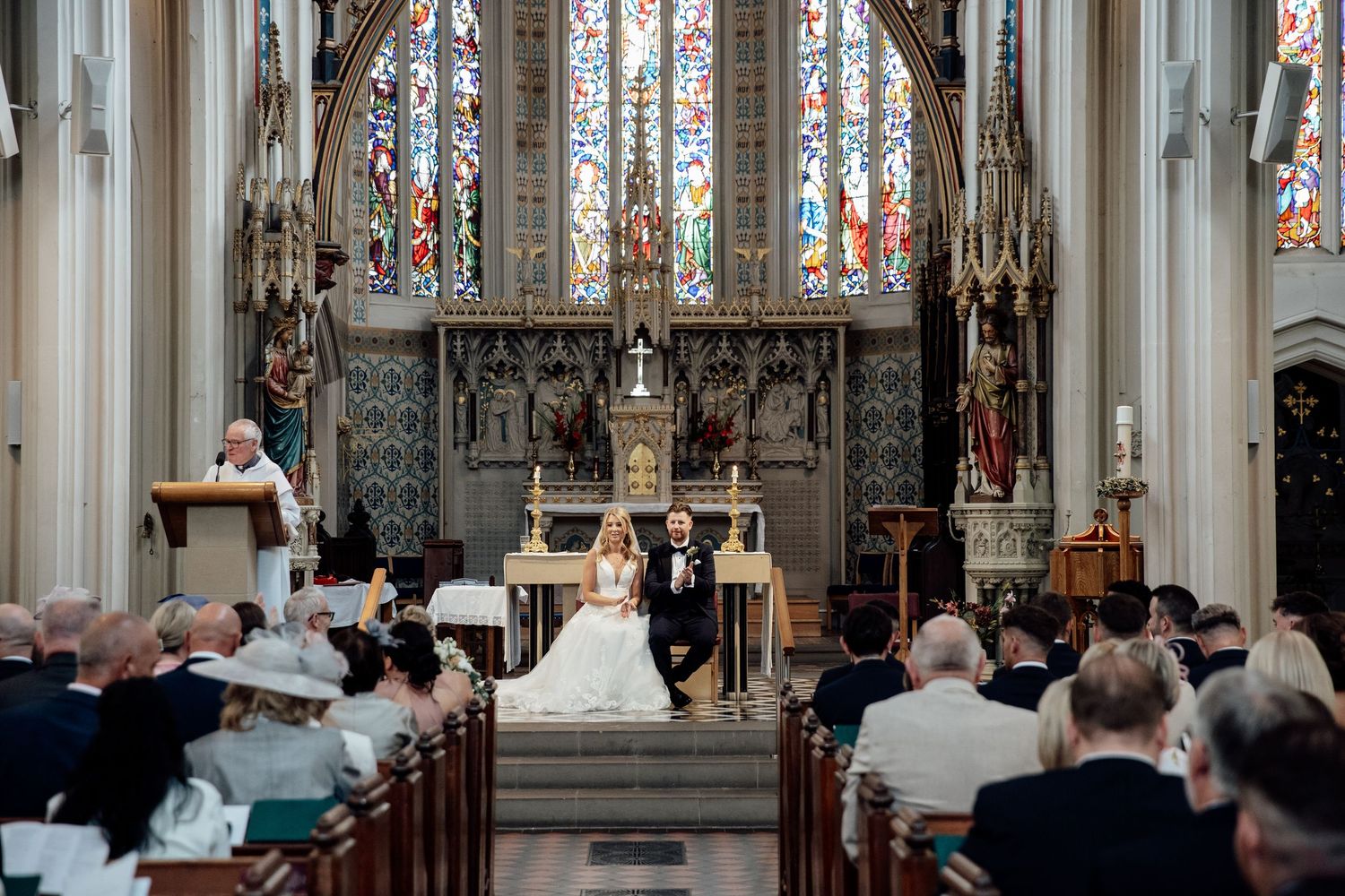 Gothic church interior with stained glass windows and ornate architectural details.
