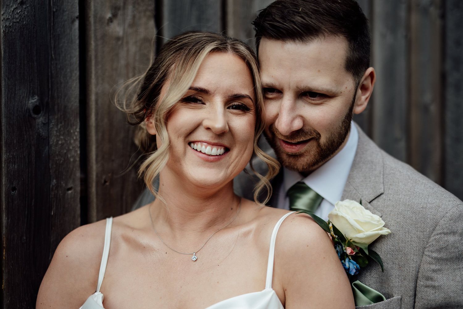 Intimate wedding couple moment against dark wooden backdrop.