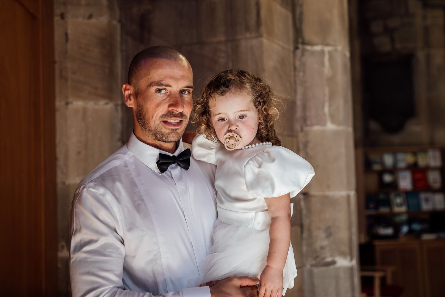 A formal portrait in an elegant stone interior setting during a wedding celebration.