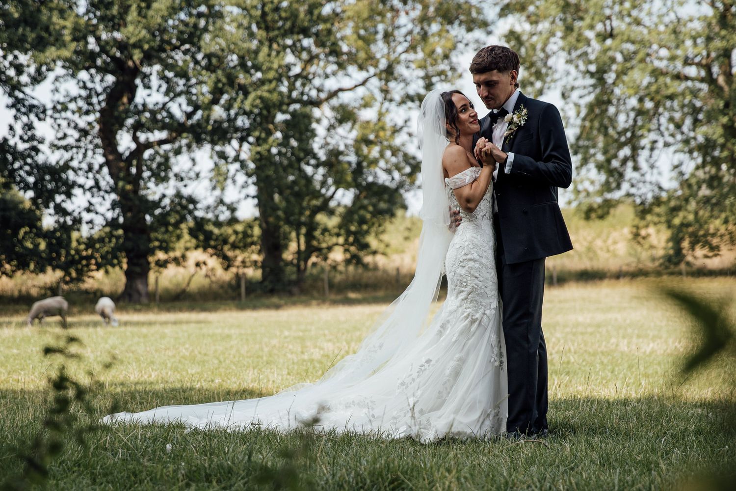 A romantic wedding portrait of a couple embracing in a sunlit meadow.