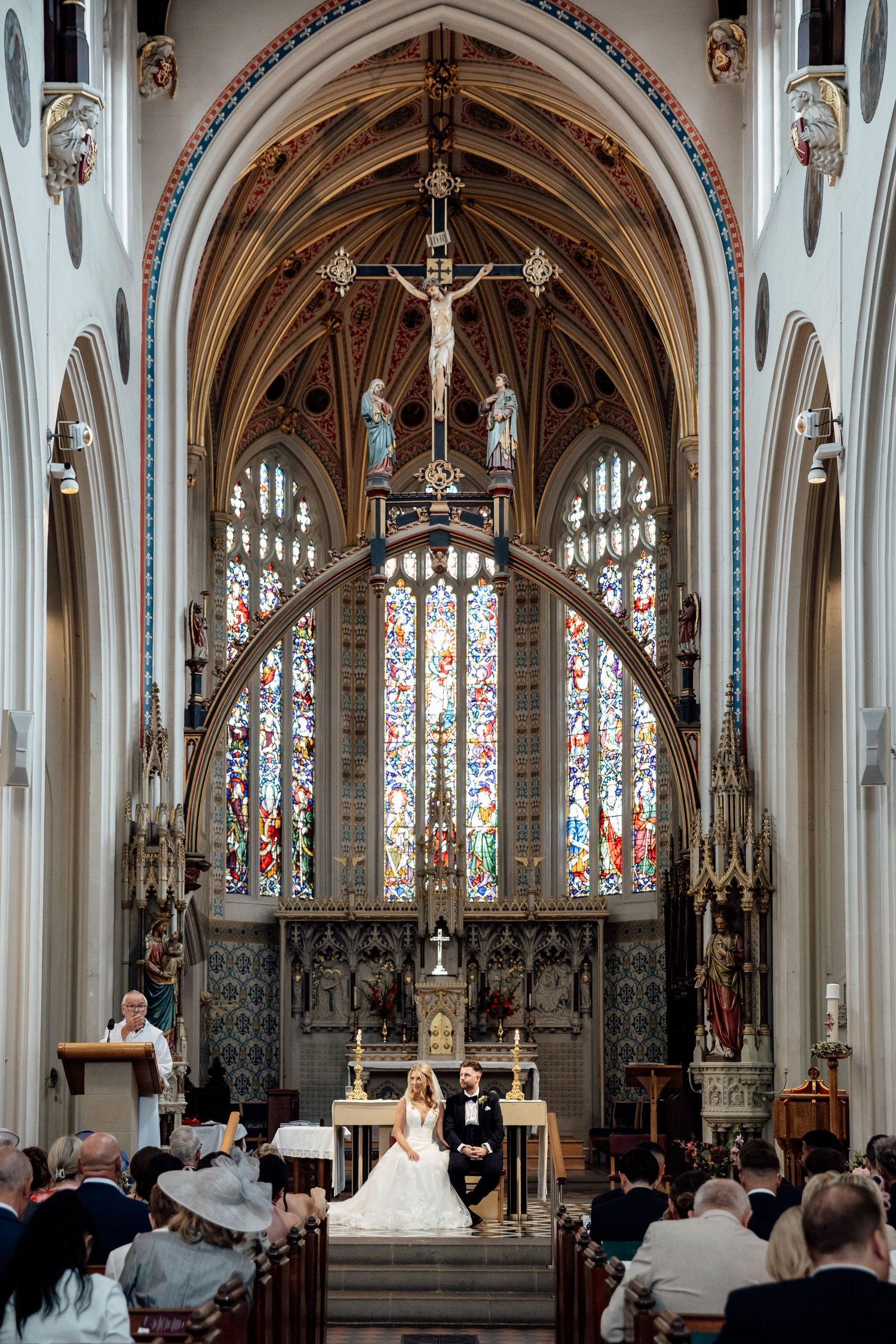 Gothic church interior with stunning stained glass windows and vaulted arches during wedding ceremony.
