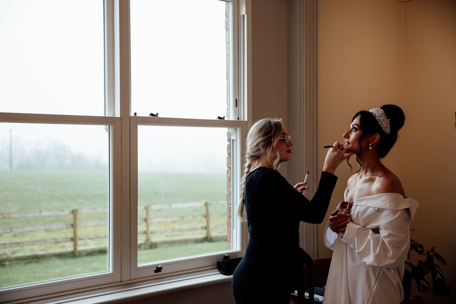 Wedding preparations by a bright window with natural light streaming in.