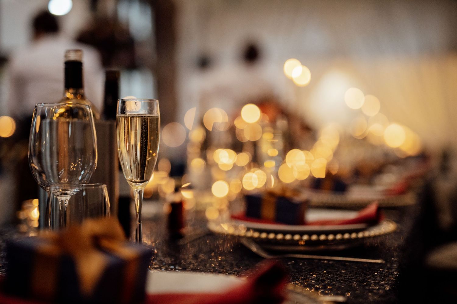 Wedding reception table settings with bokeh lights in warm ambient lighting.