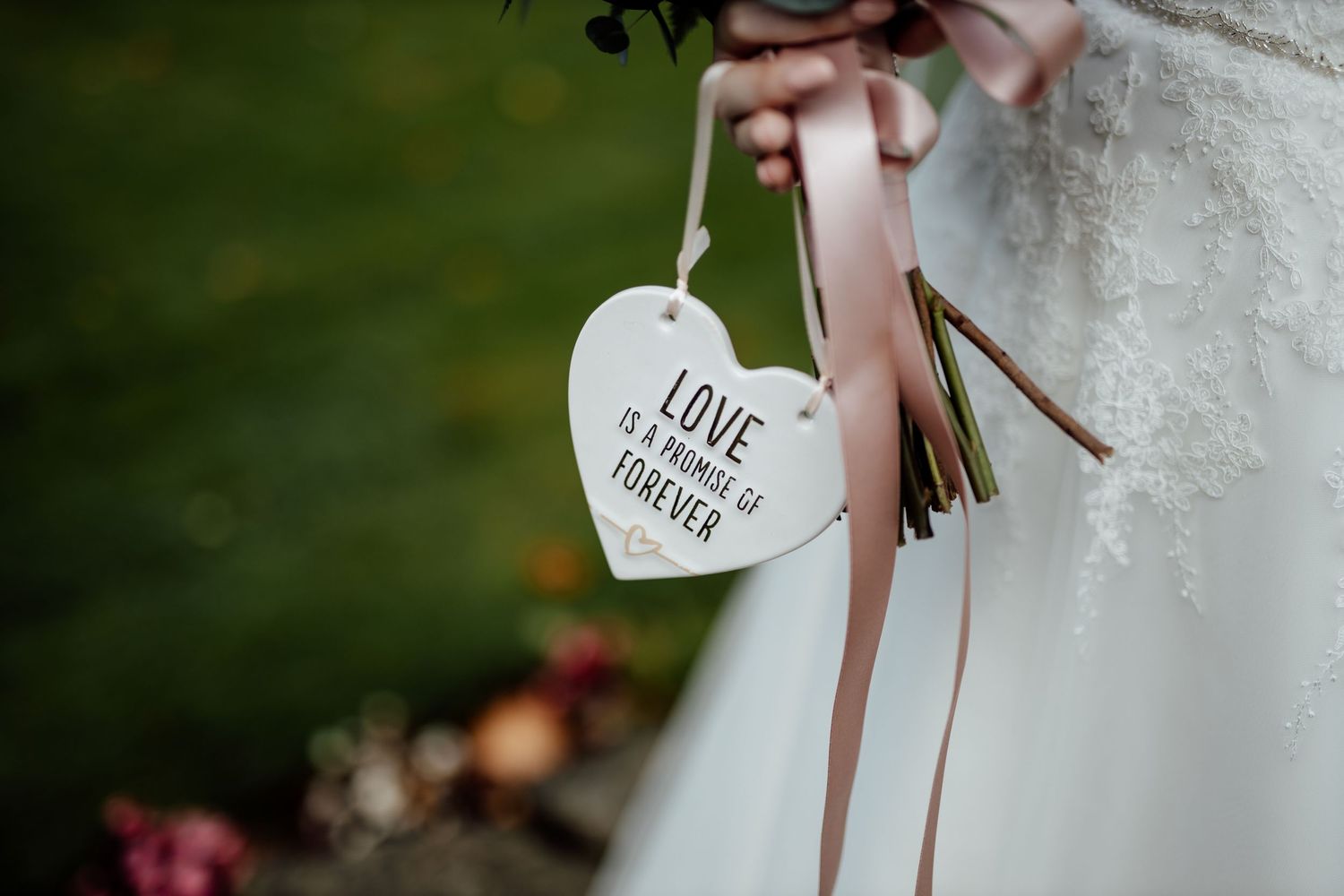 Decorative white love sign with ribbon details in outdoor wedding setting.