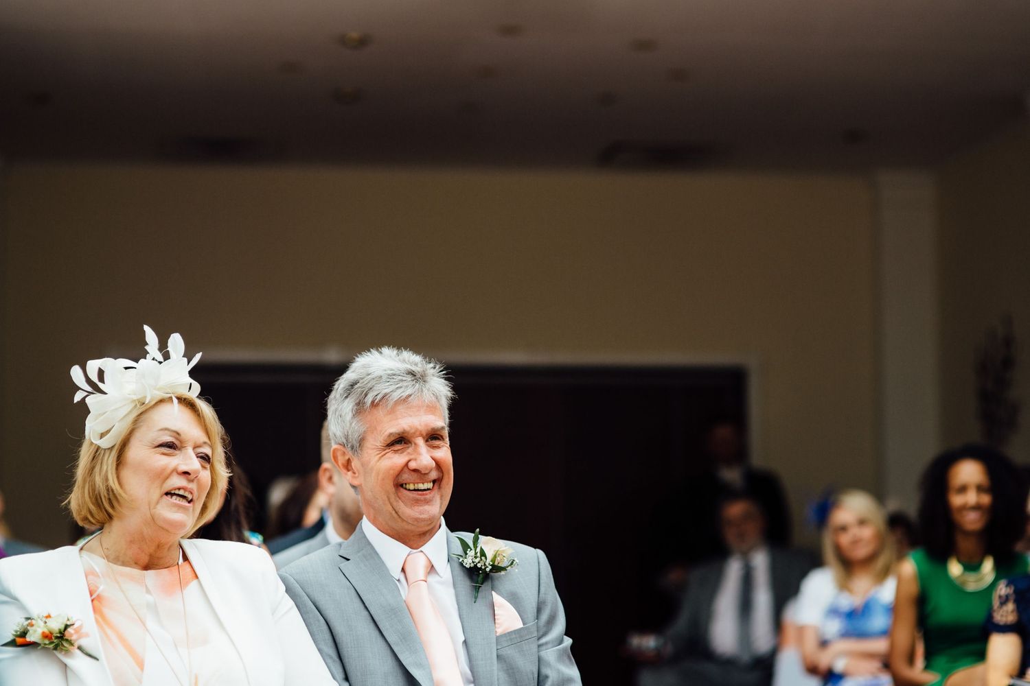 Wedding guests seated in rows during an indoor ceremony with natural lighting.