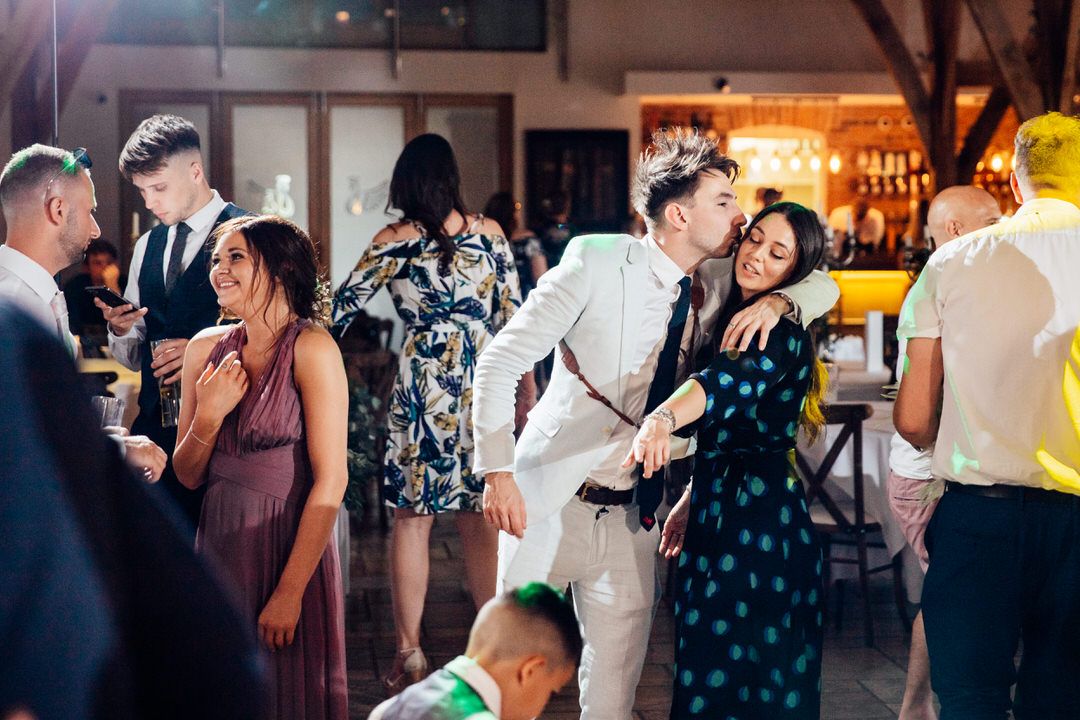 Guests dancing and celebrating at an indoor wedding reception with ambient lighting.