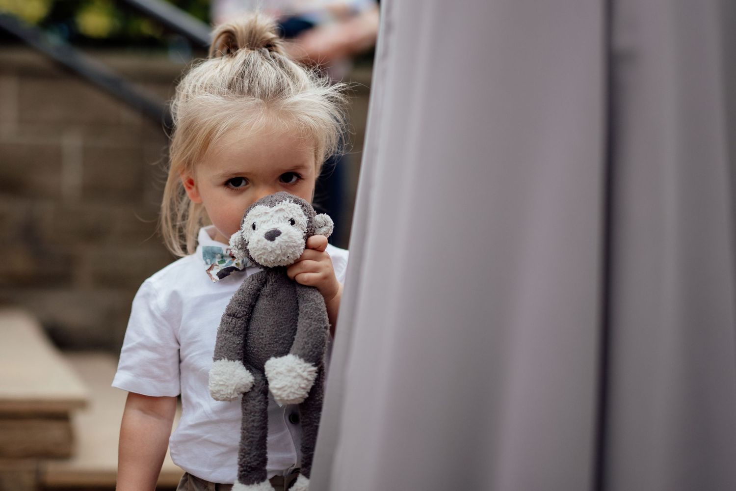 Small child holding a plush toy animal near a window.