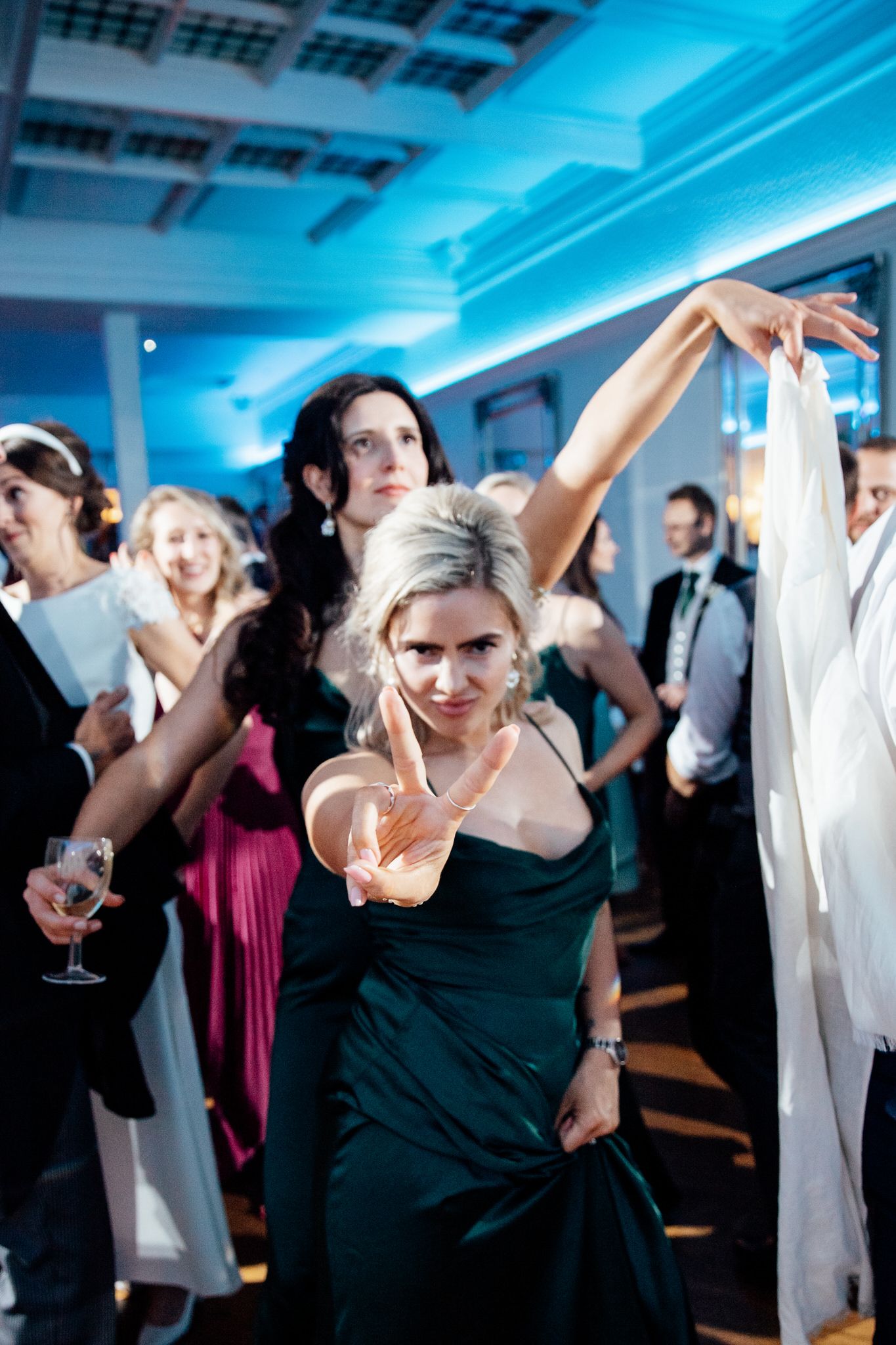Dance floor filled with wedding guests under dramatic blue lighting.