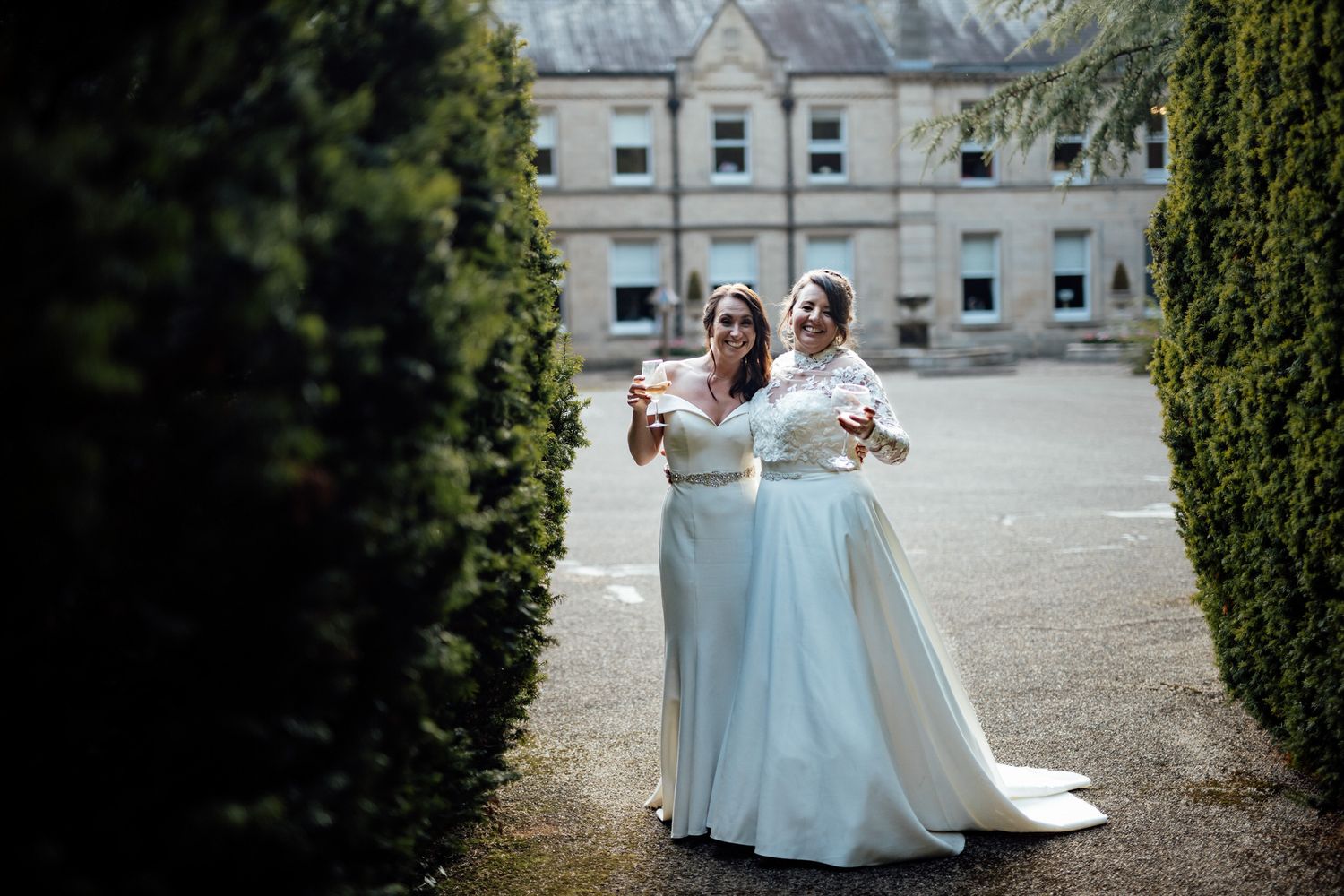 Two people in white dresses walking together on a stone pathway.