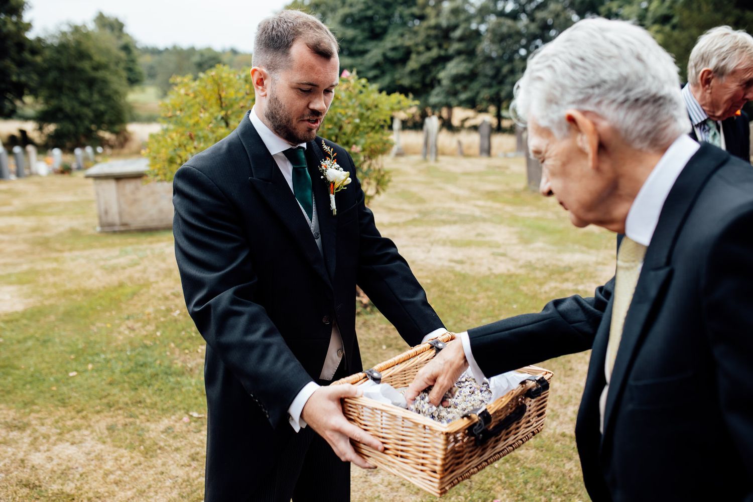 Wedding guests passing wicker baskets during an outdoor gathering.