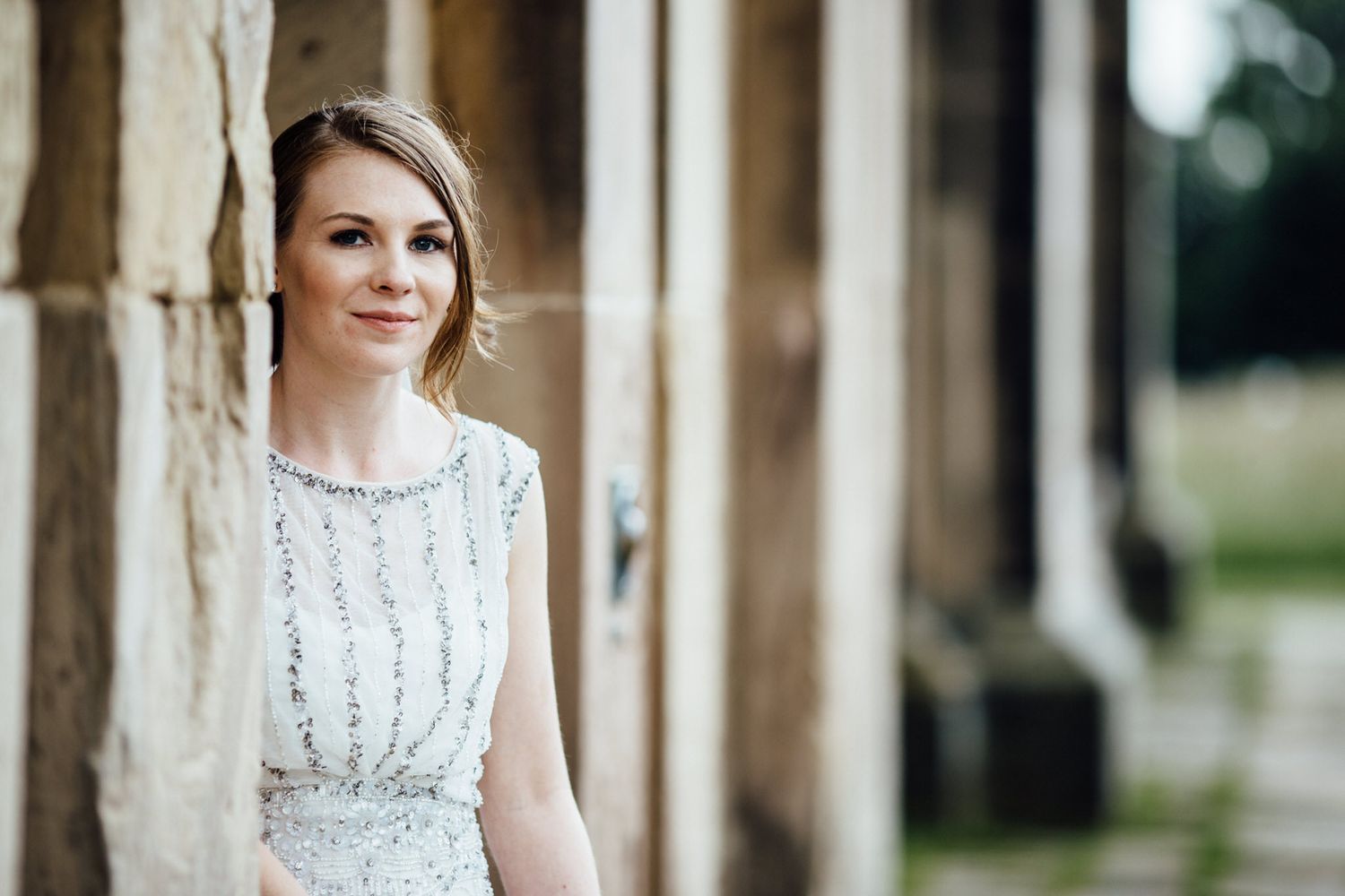 Elegant wedding portraits captured in a historic stone colonnade with classic architecture.