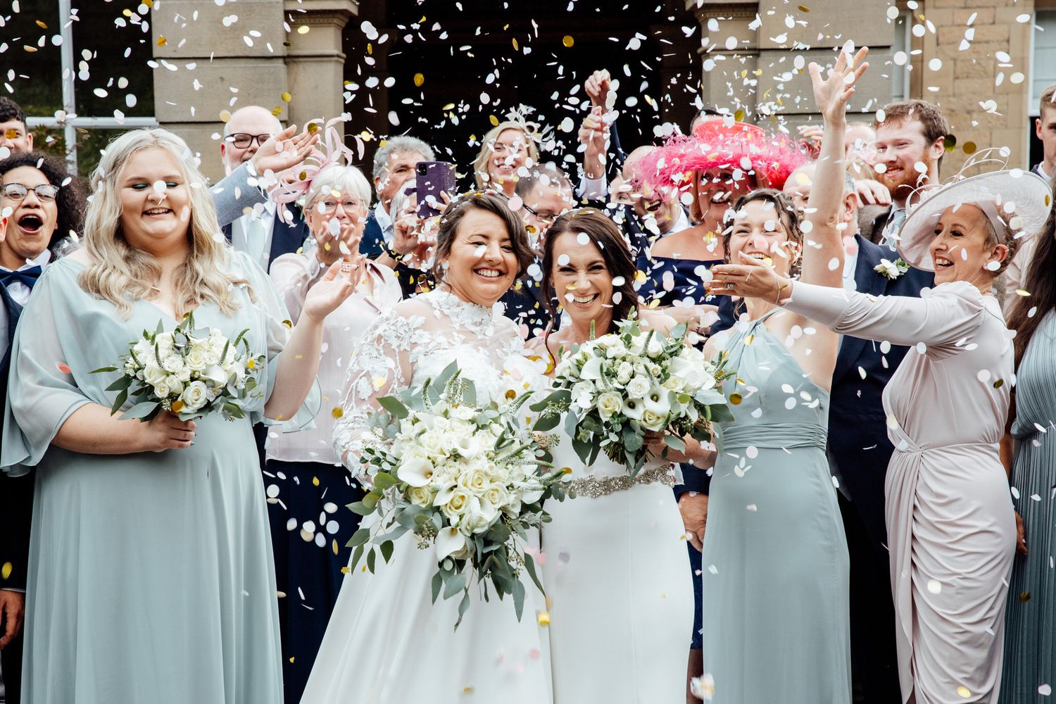 Wedding guests shower the newlyweds with confetti during an outdoor celebration.