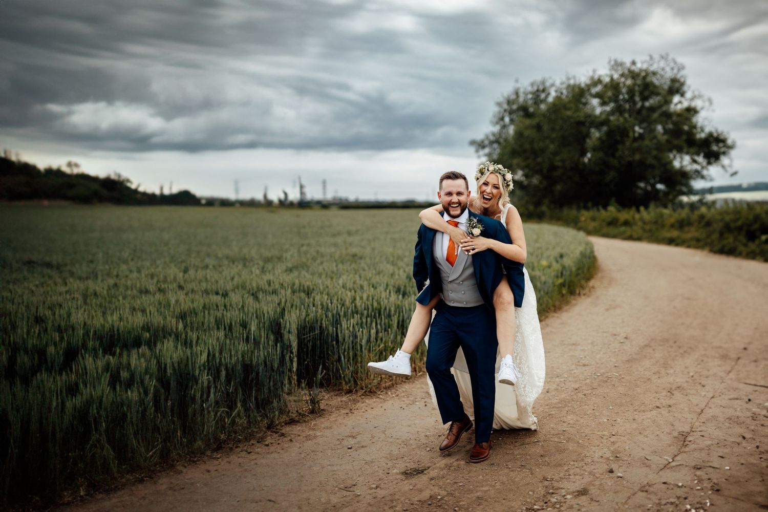 Couple poses on a rustic country path surrounded by wheat fields.