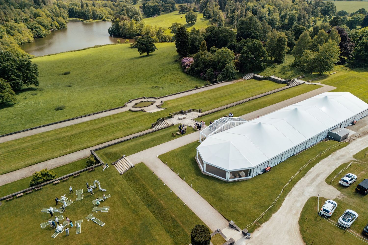 Aerial view of a large white wedding tent venue surrounded by lush green countryside.