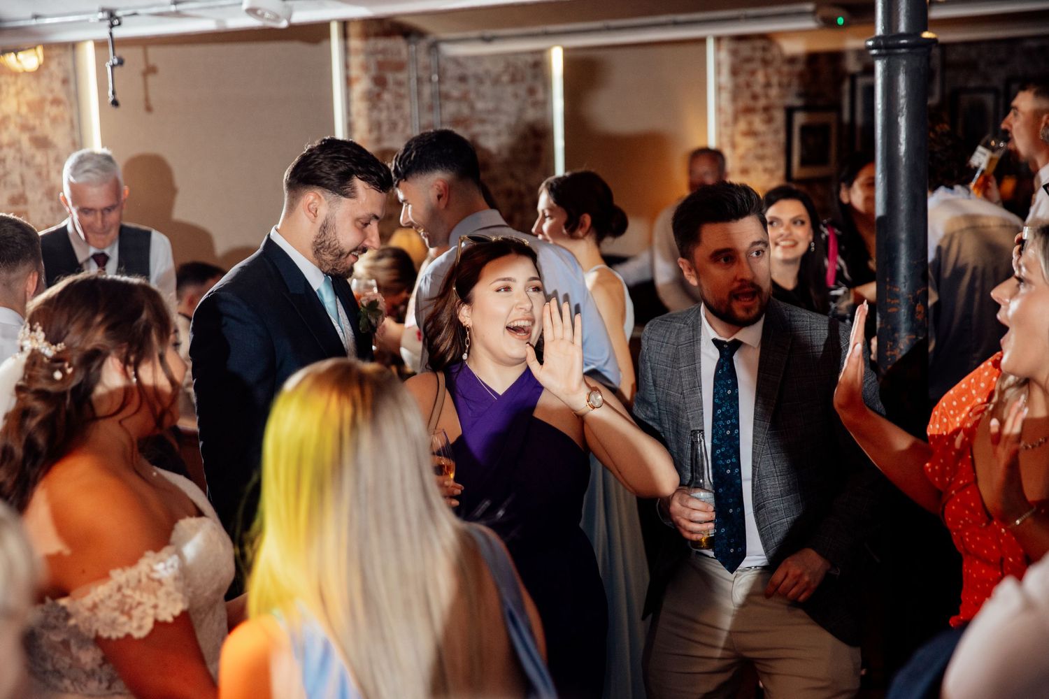 Wedding reception party with guests dancing and celebrating indoors.