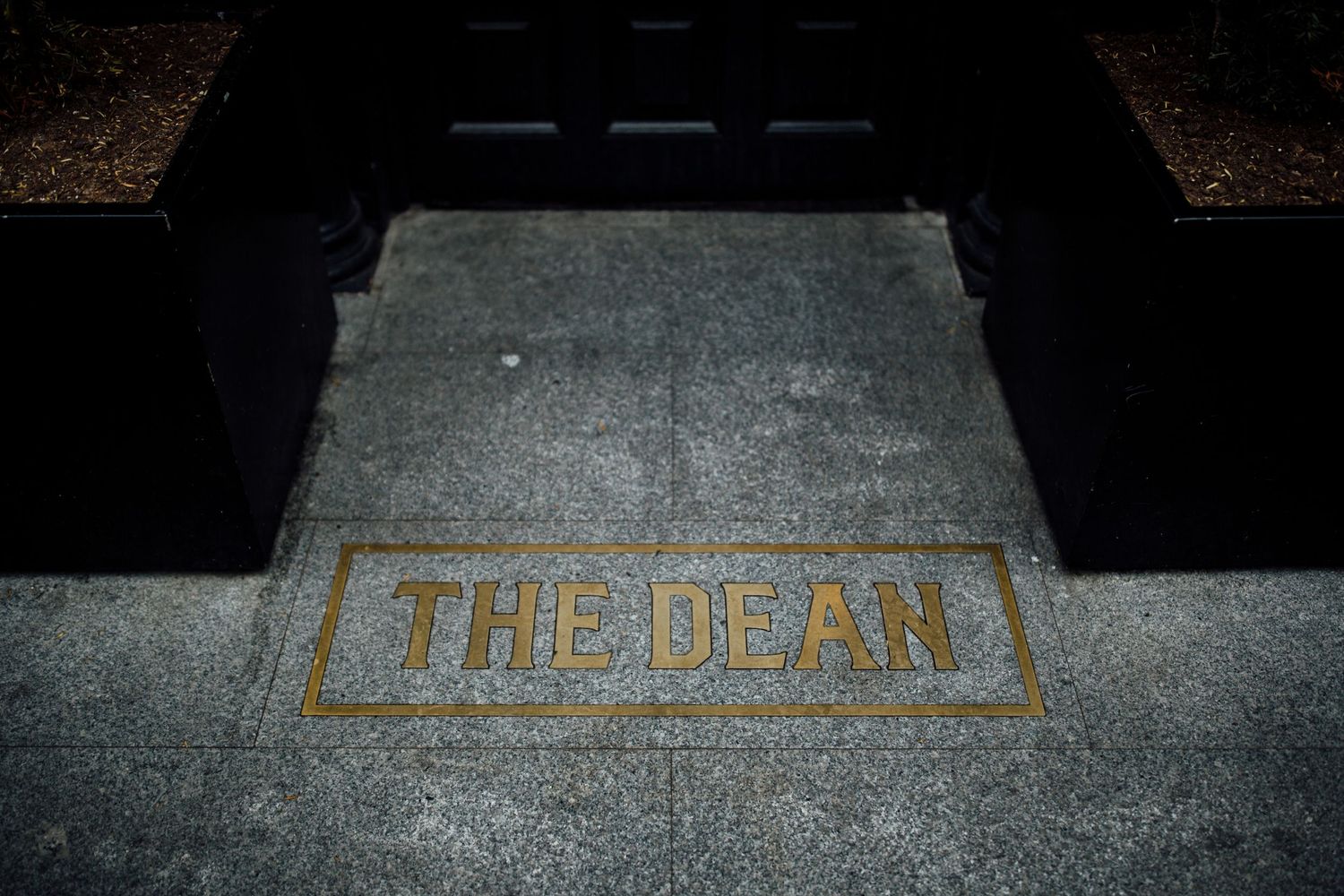 Gold lettering reading 'THE DEAN' embedded in stone or concrete.