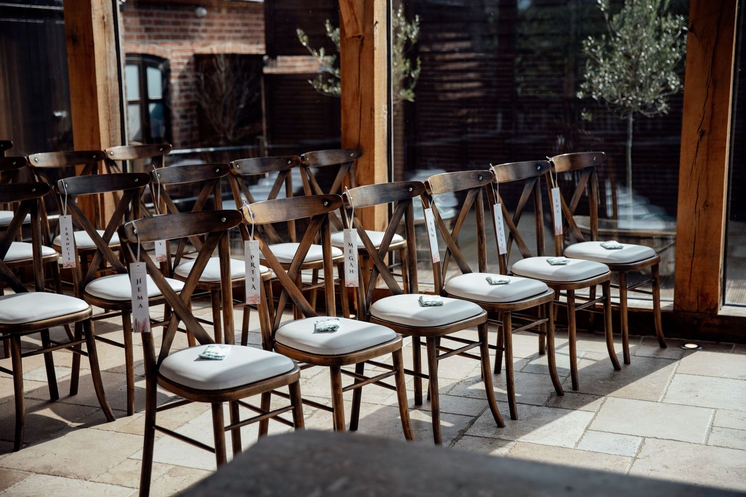 Empty wooden chairs lined up at rustic indoor wedding venue.