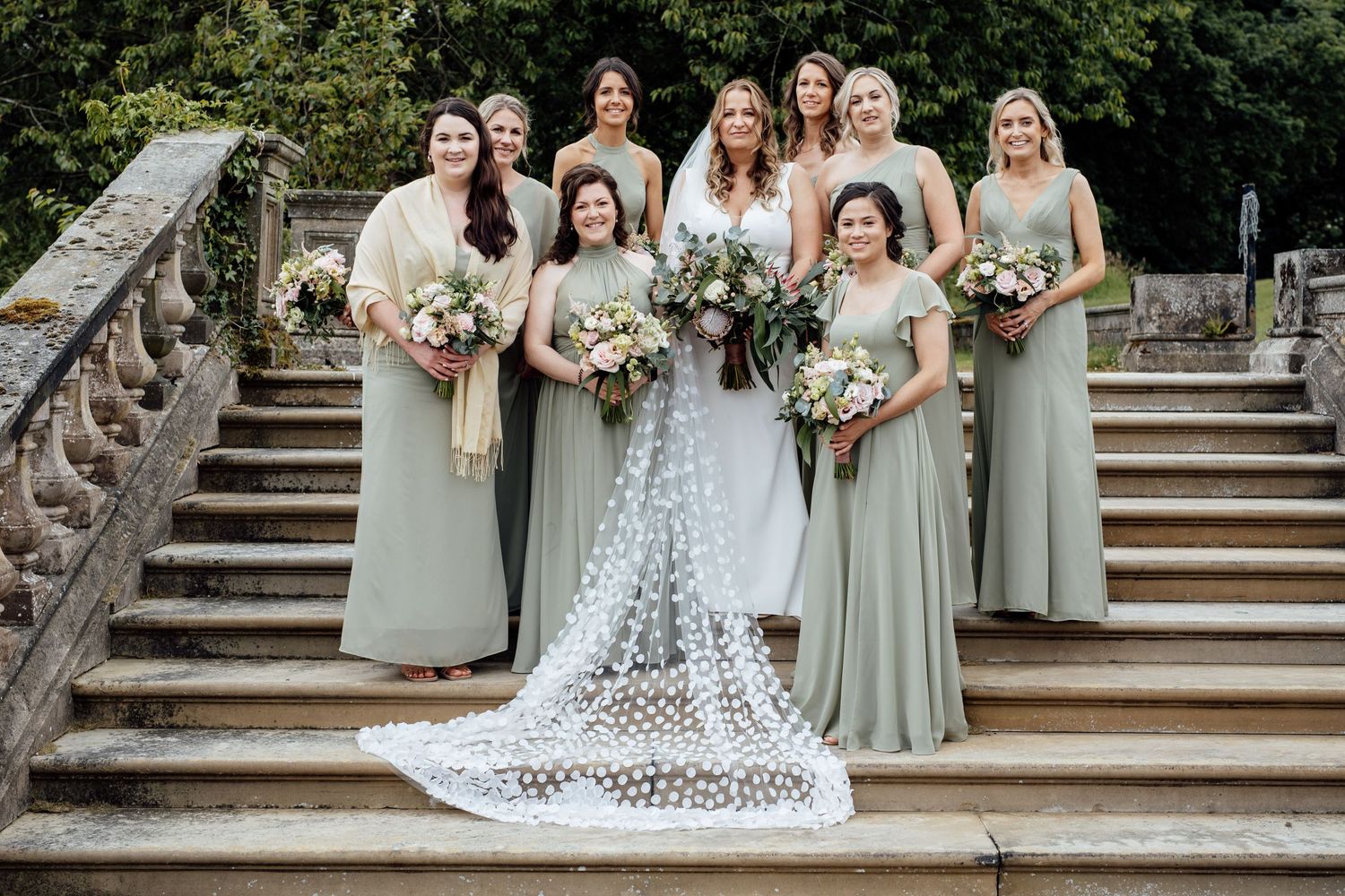 Wedding party posed on grand stone steps outdoors.