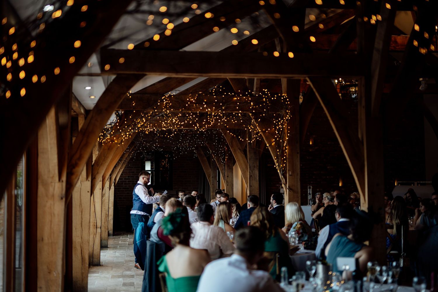 String lights create a magical ambiance in a rustic wooden barn reception venue.