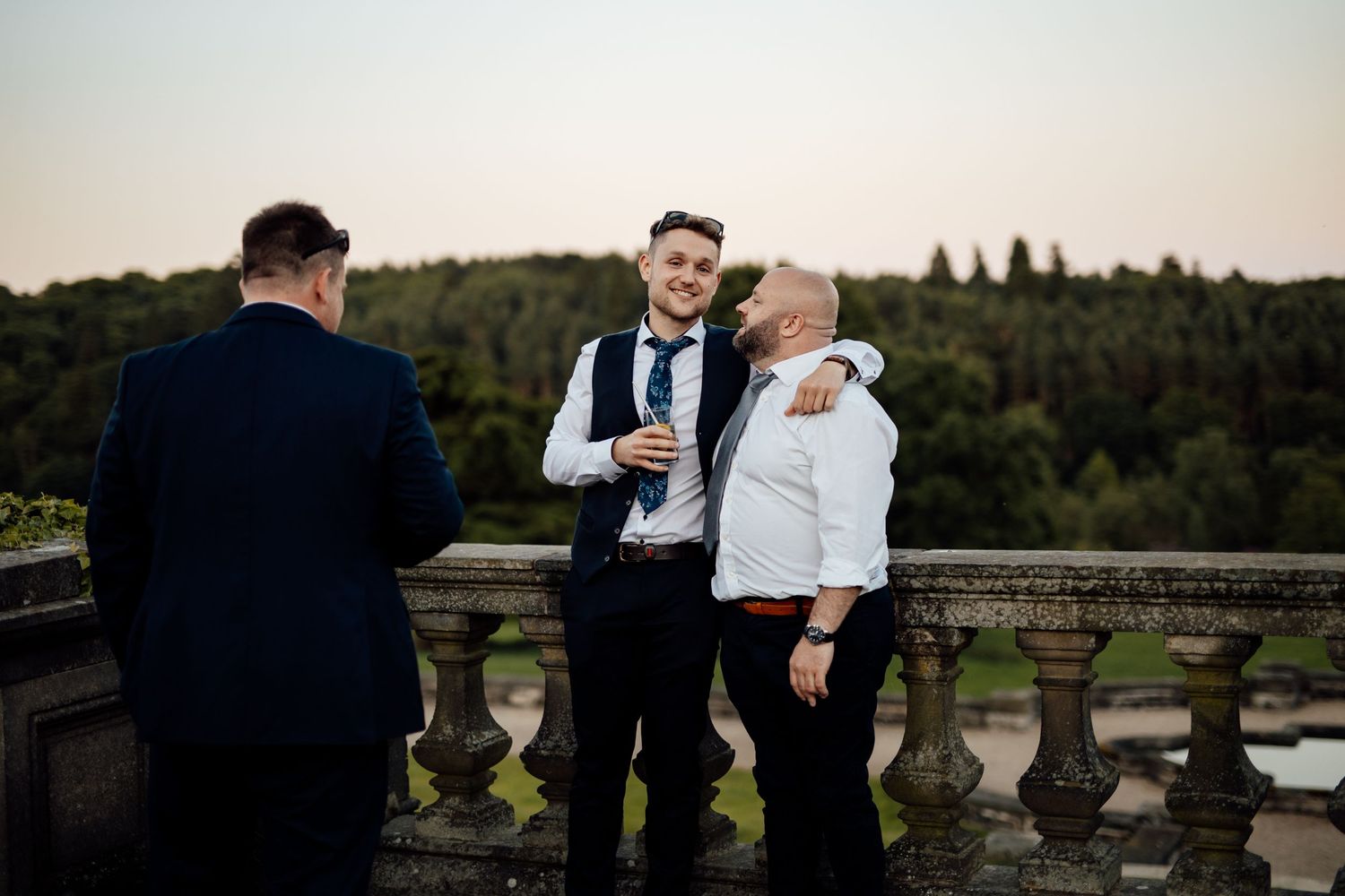 Outdoor wedding celebration on a stone terrace overlooking scenic countryside views.