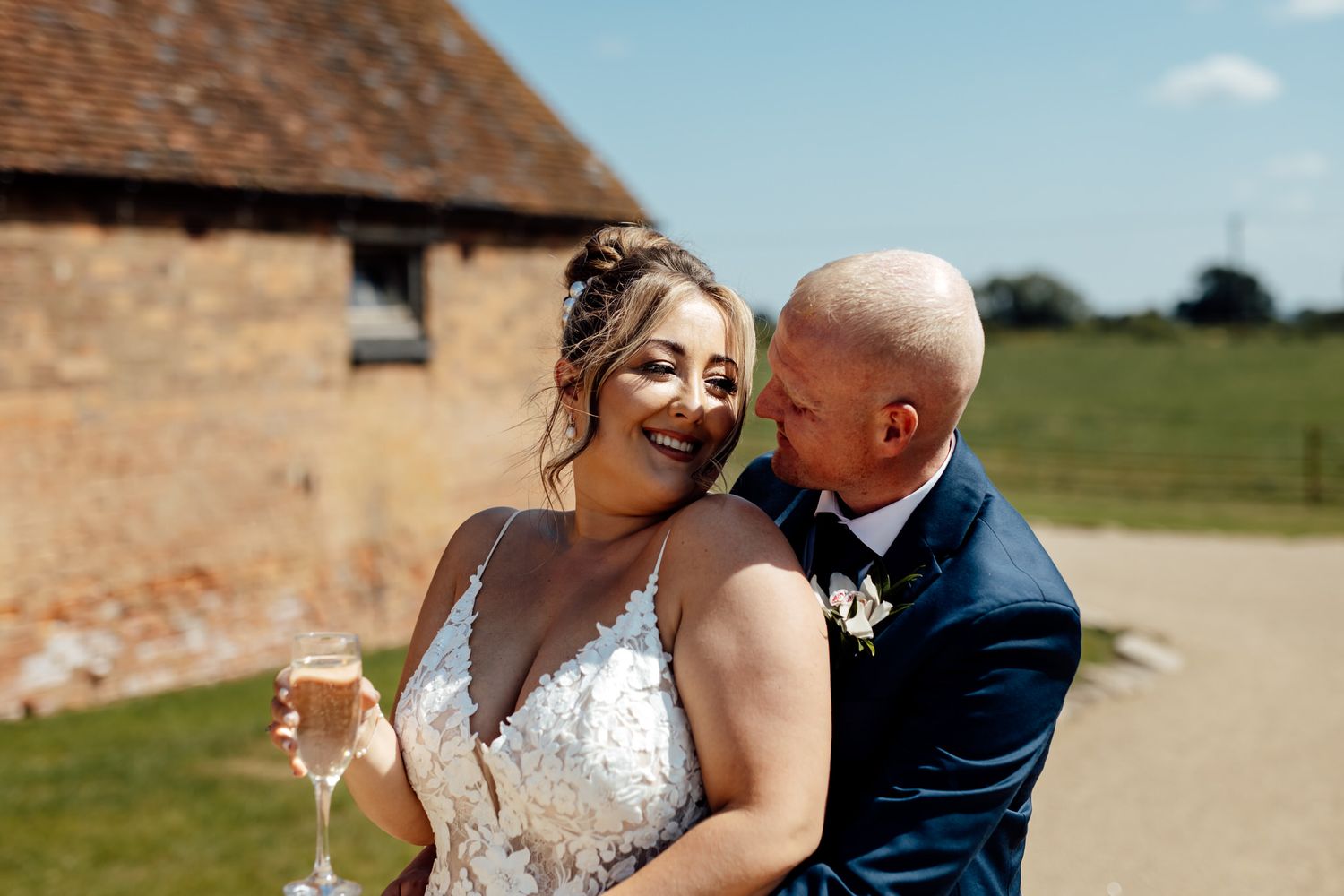 Couple celebrates their wedding day in a sunny outdoor field.